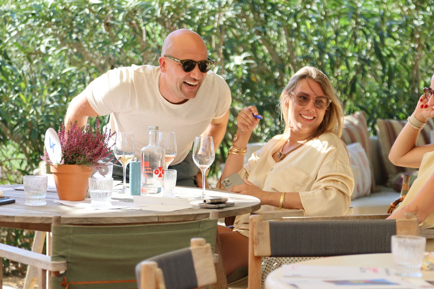 A guest leans in, laughing, to talk with a woman at her table.